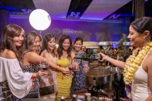 group of women holding out wine glasses while someone pours them wine