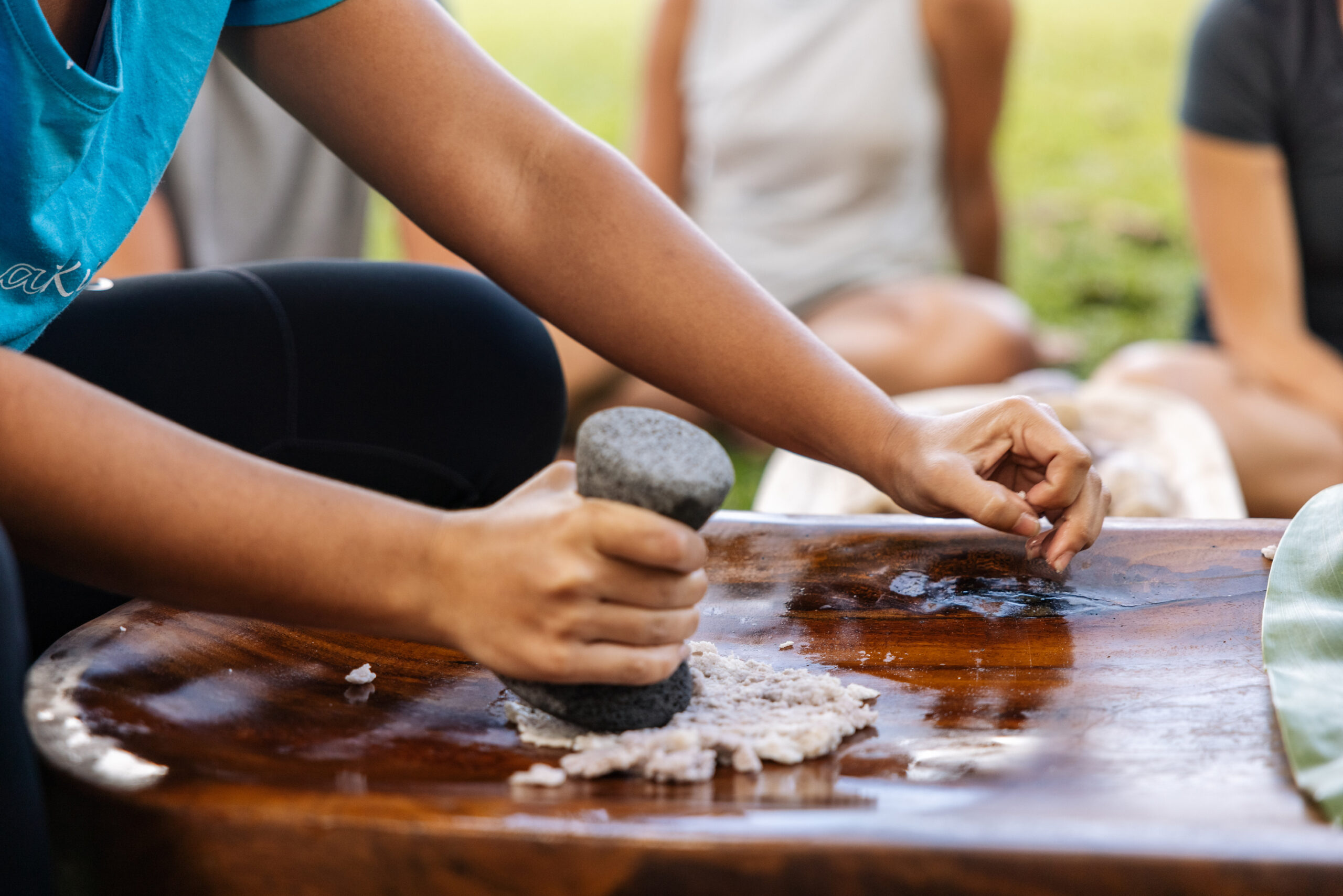 pounding taro on wooden board with stone making paiai