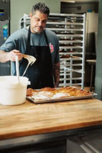 David Escobar, owner of Papi's Ohana, putting frosting on cinnamon rolls.